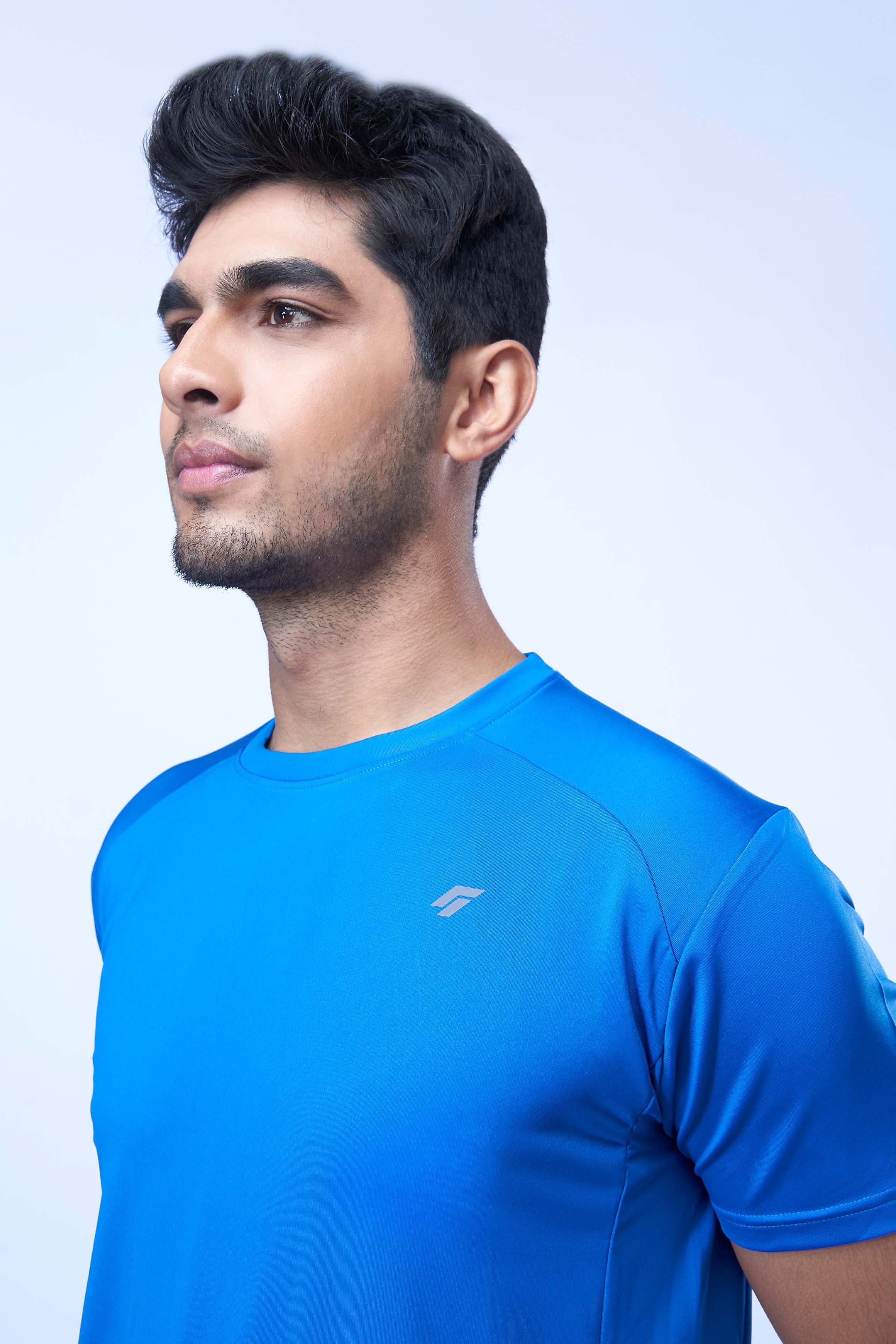 Man posing in a blue recycled polyester activewear t-shirt highlighting the design, against a white background.