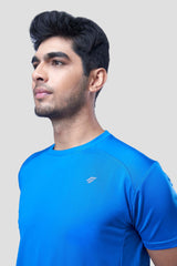 Man posing in a blue recycled polyester activewear t-shirt highlighting the design, against a gray background.