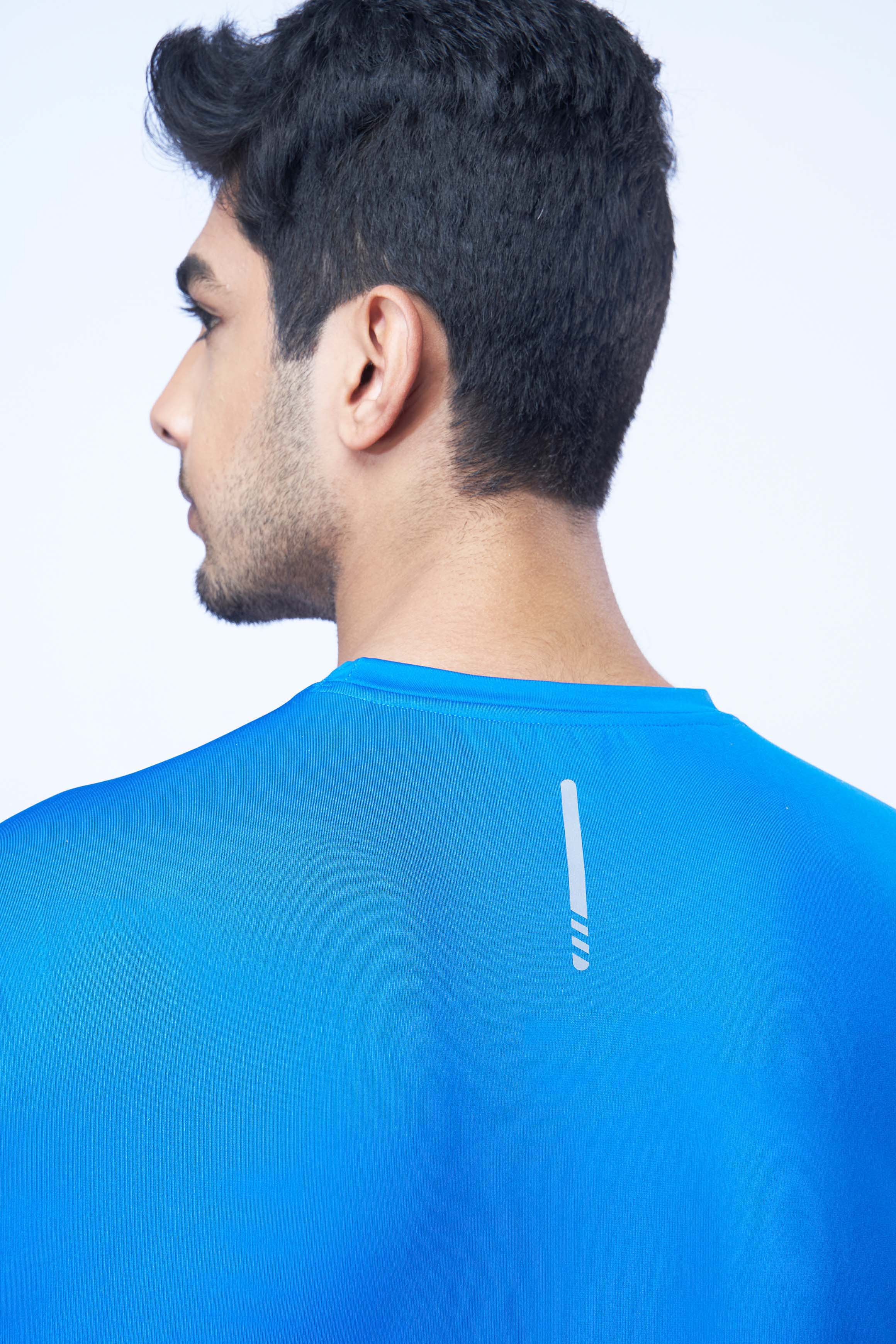 Back view of a man wearing a blue recycled polyester activewear t-shirt emphasizing the material.