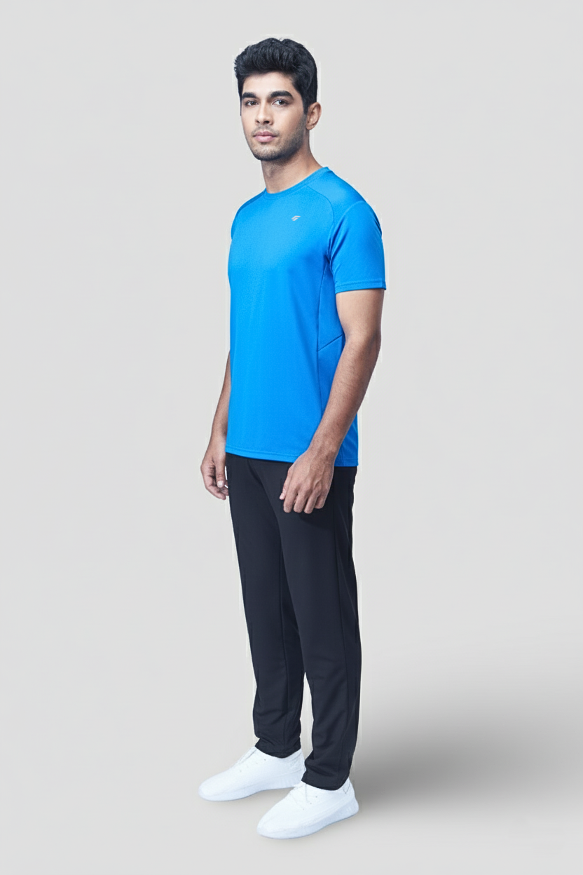 Man wearing a blue active t-shirt and black pants on a light gray background
