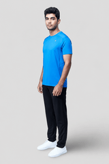 Man wearing a blue active t-shirt and black pants on a light gray background
