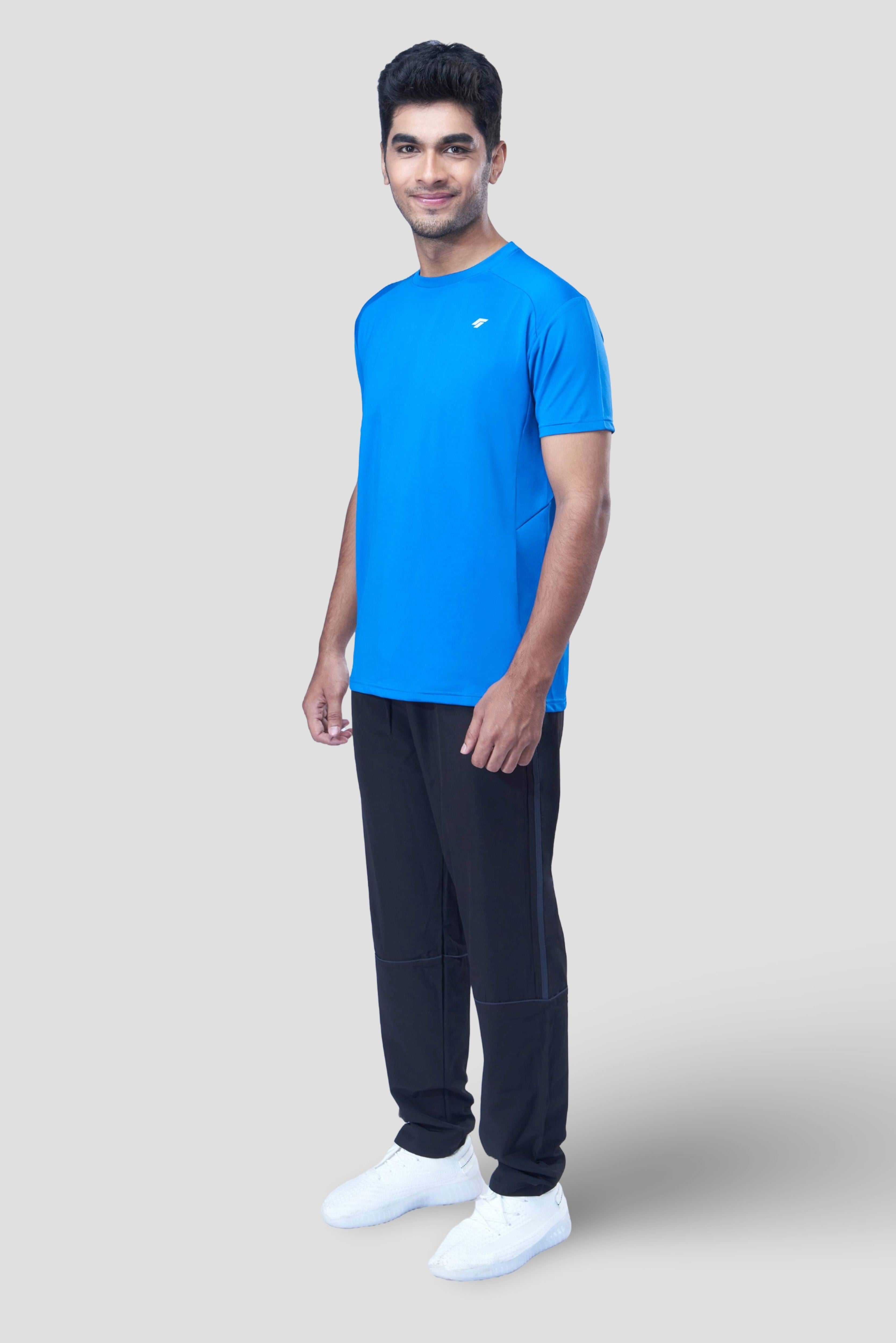 Man posing in a sustainable blue activewear t-shirt and joggers in front of a gray background.