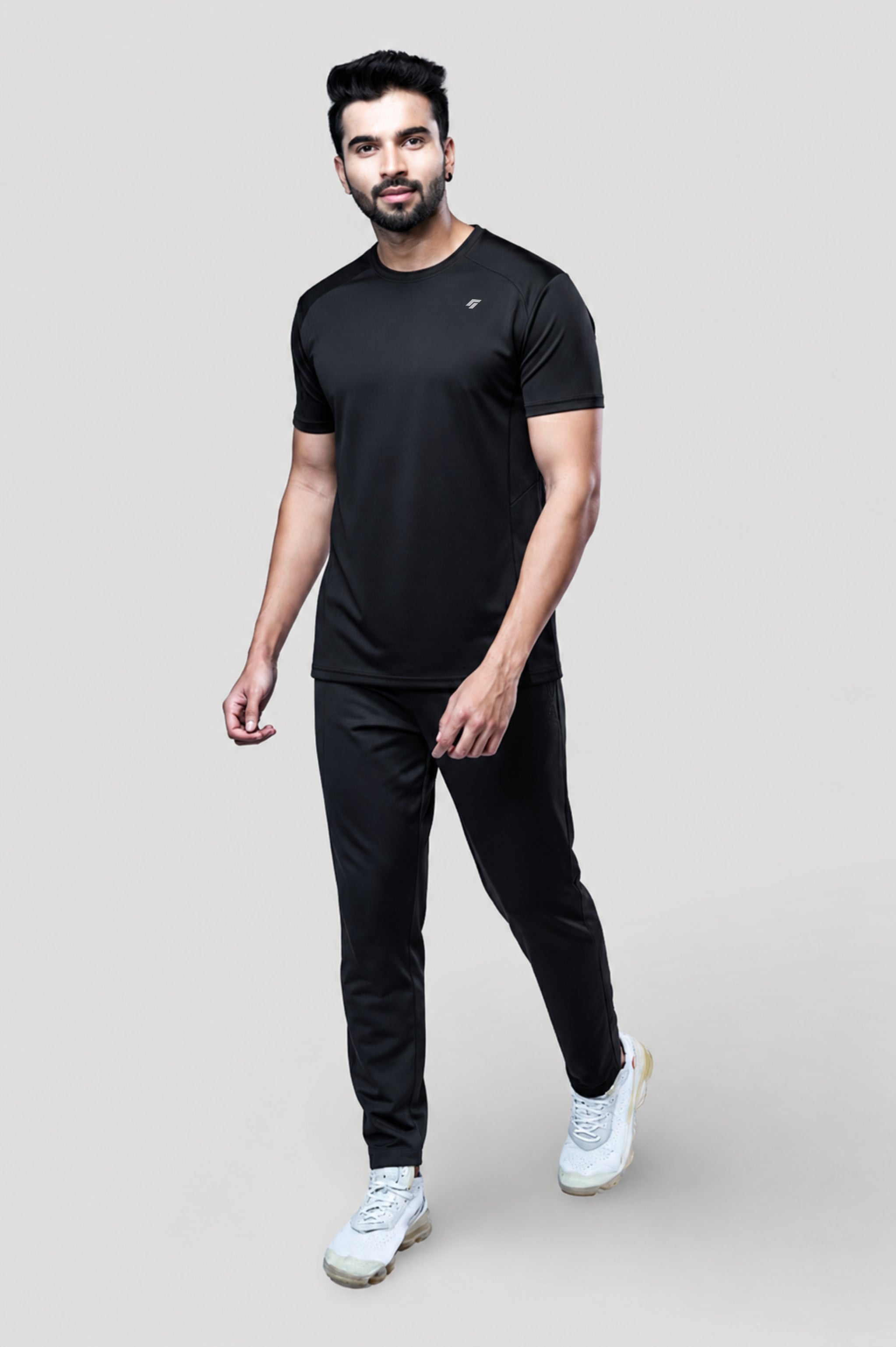Man wearing a black active t-shirt and gray joggers against a light gray background