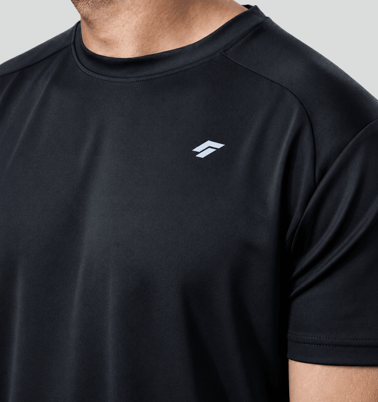 Close-up of man wearing black active t-shirt with a logo on a gray background