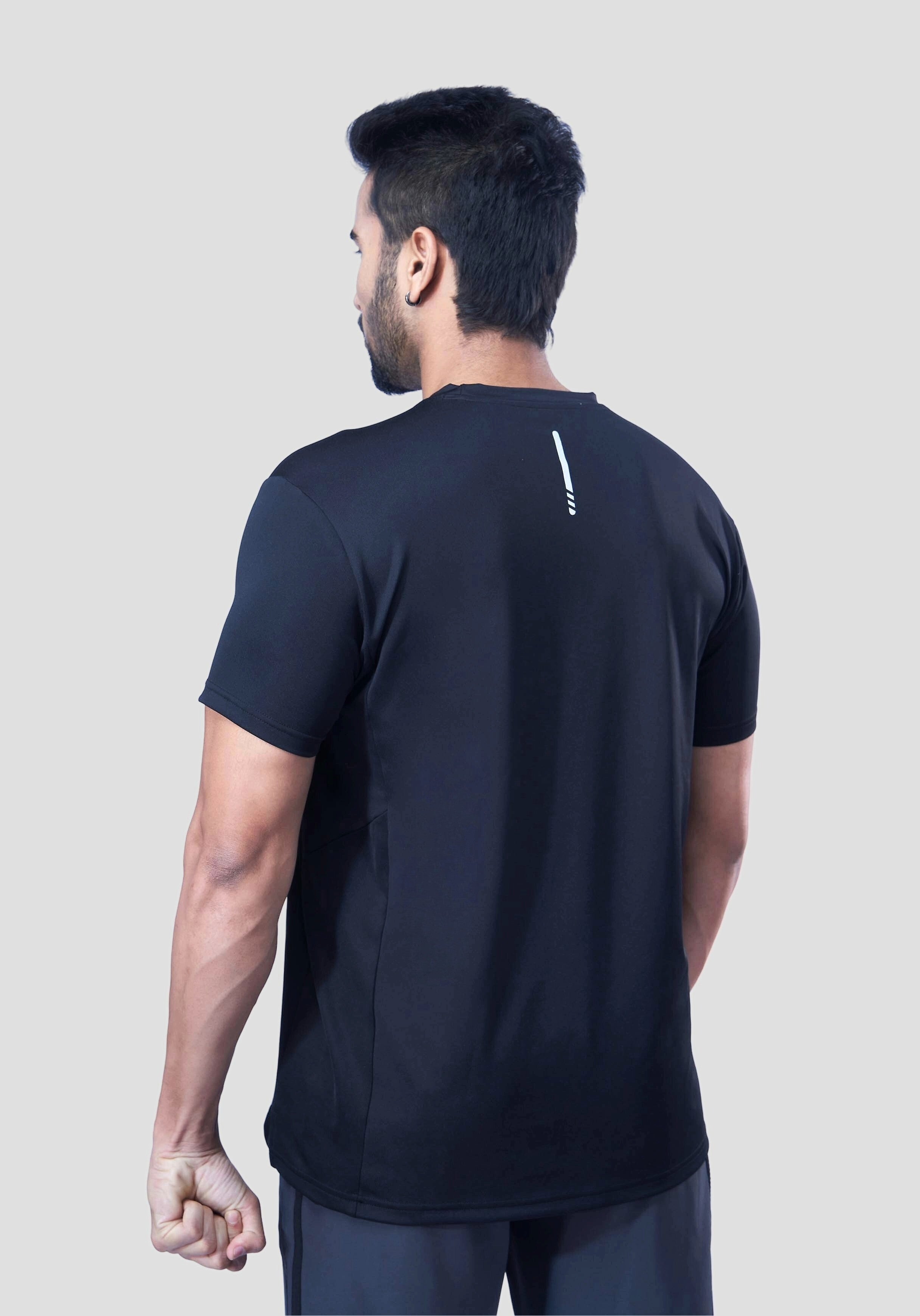 Back view of a man wearing a recycled polyester black activewear t-shirt against a gray background.