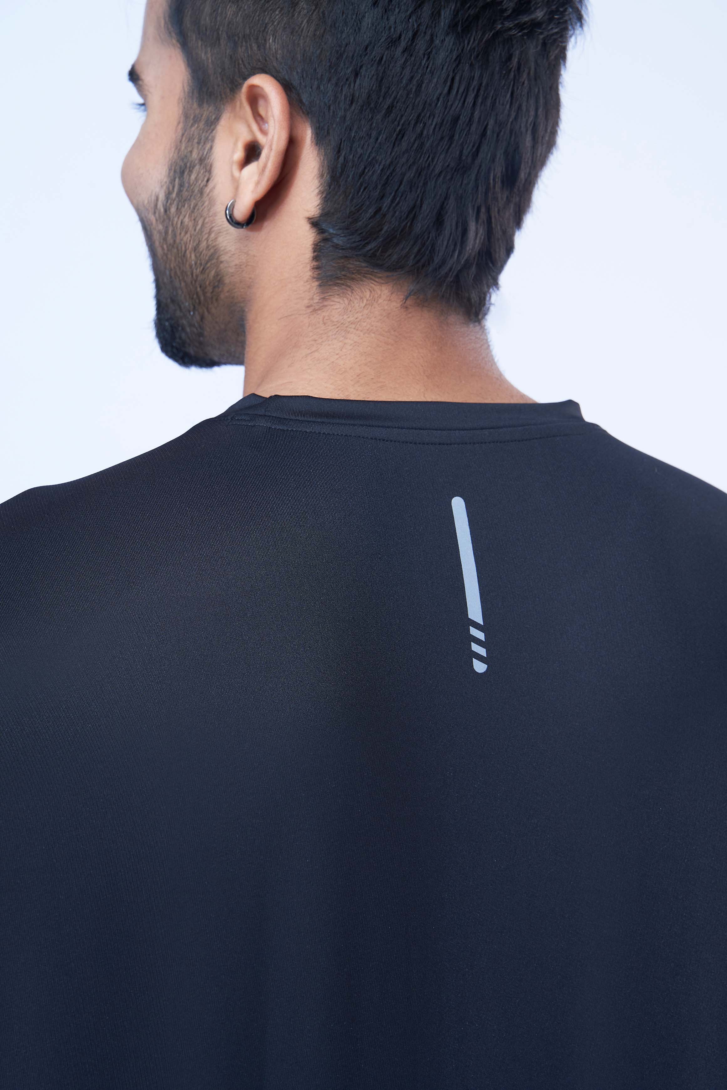 Back view of a man wearing a black recycled polyester activewear t-shirt emphasizing the material.