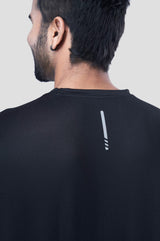 Back view of a man wearing a recycled polyester black activewear t-shirt against a gray background.