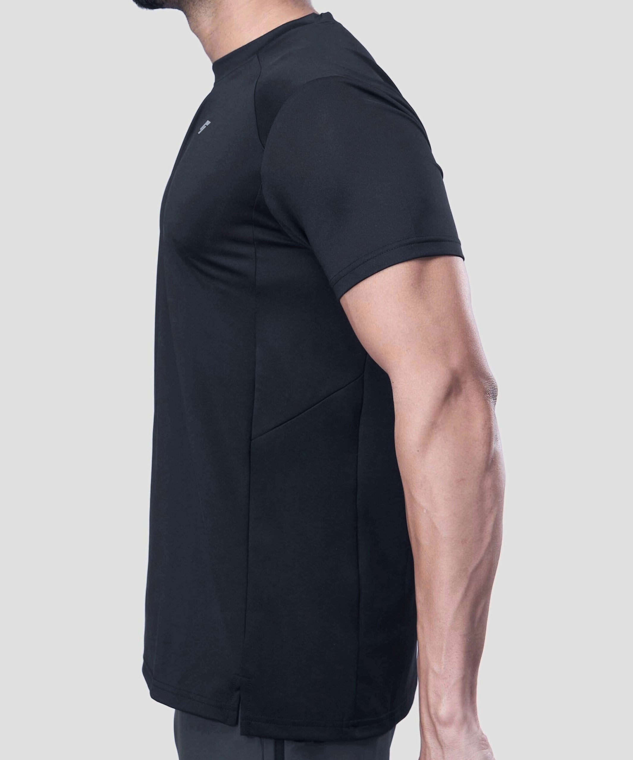 Man wearing a black active t-shirt showing side tee design on a light gray background