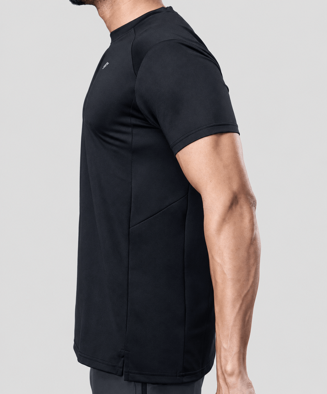 Man wearing a black active t-shirt showing side tee design on a light gray background