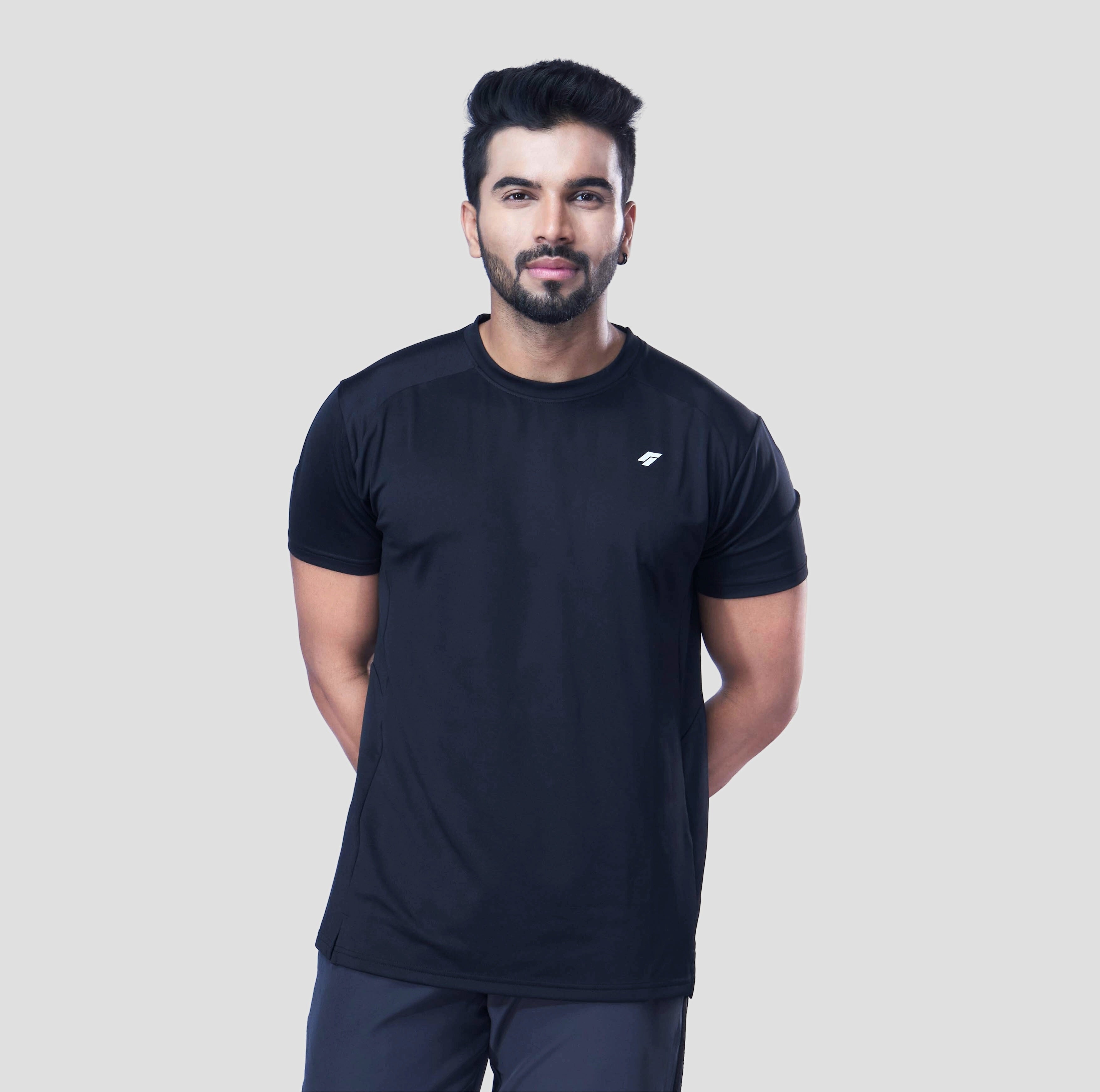 Man posing in a comfortable black recycled polyester activewear tee against a gray background.