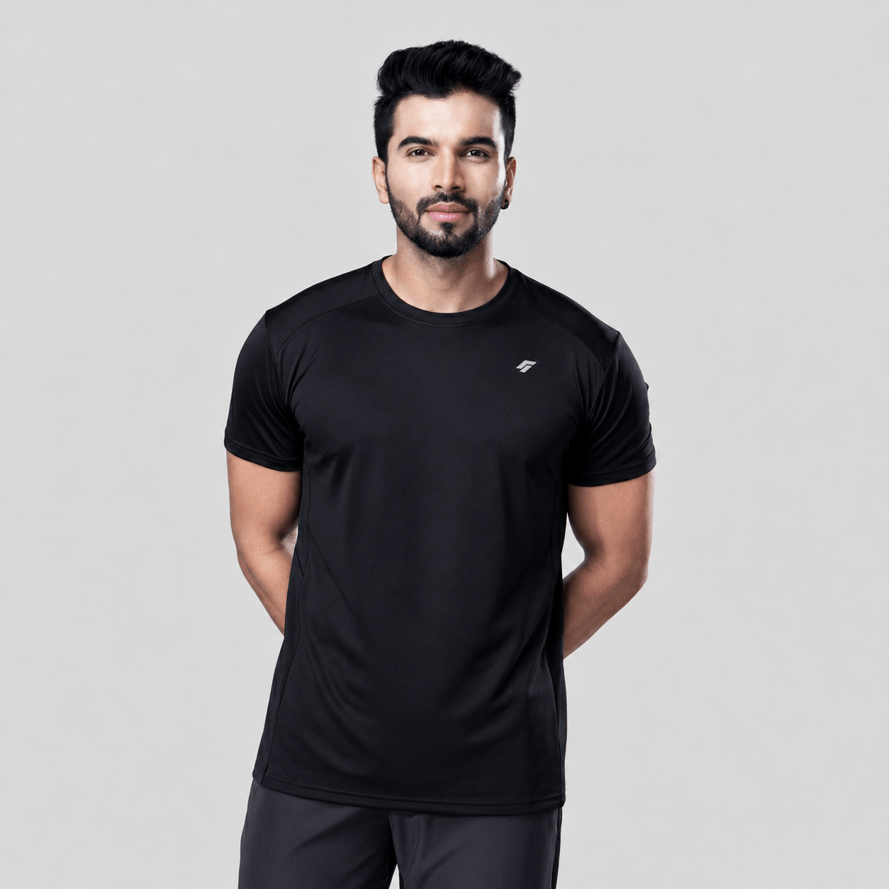 Man wearing a black active t-shirt and gray joggers against a light gray background